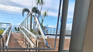 A view through a window of a staircase leading outside, with a clear sky and palm trees visible. - Mactan Newtown Poolside View near Airport & Beach (Lapu-Lapu)