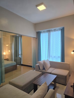 A modern hotel room with a bed, a sofa, a coffee table, and a desk.
