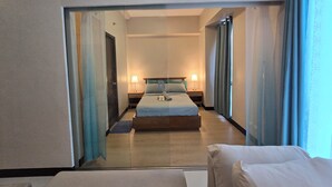 A hotel room with a bed, bedside tables, a mirror, and a window with curtains. - Mactan Newtown Poolside View near Airport & Beach (Lapu-Lapu)