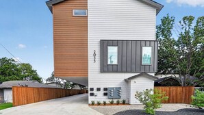 A modern two-story house with a combination of wooden and white siding, a visible garage, and a front yard with landscaping. - 2BR Retreat | 5 Min Downtown + Medical District (Dallas)