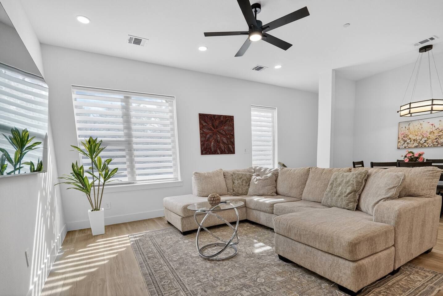 Ein Wohnzimmer mit Ecksofa, Couchtisch, Stehlampe und Deckenventilator.