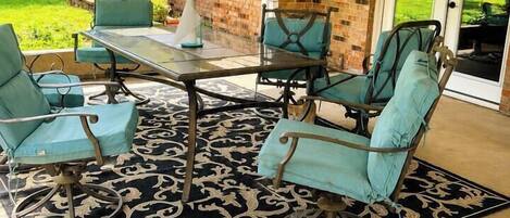An outdoor patio with a brick wall, a glass door leading outside, and a table with chairs.