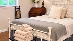 A bedroom with a bed, a nightstand, a lamp, a dresser, and a window with blinds. - Shady Pecan Farmside (Red Oak)
