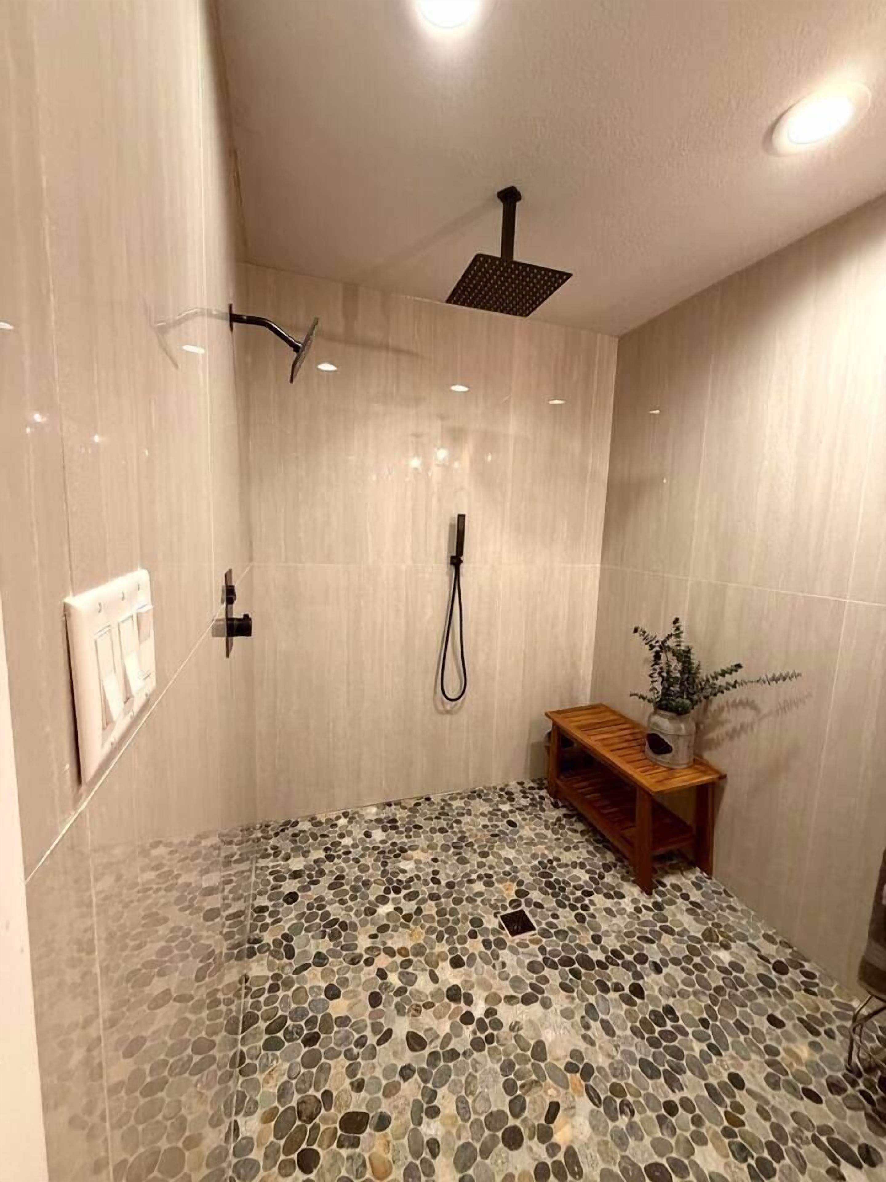 A shower with a rain showerhead, a handheld showerhead, and a handheld shower attachment.