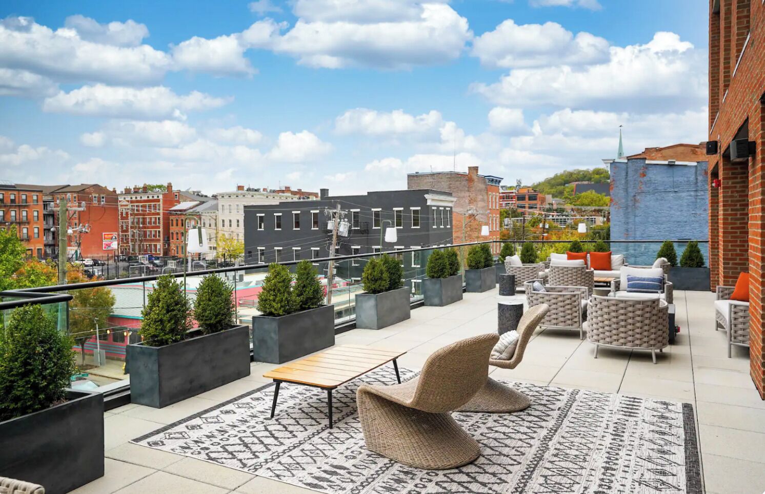 Una terraza en la azotea con mobiliario exterior, plantas en macetas y vistas a la ciudad.