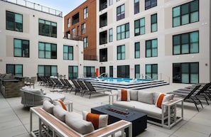 A rooftop pool area with lounge chairs, a barbecue grill, and a fire pit. - Cozy Modern 1BR in Downtown OTR, GYM, POOL (Cincinnati)