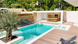 Ein Poolbereich im modernen Stil mit Holzterrasse, Liegestühlen und einer Steinmauer.