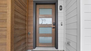 A wooden door with frosted glass panels, a metal handle, and a small mailbox on the right side. - Premium 2BR Near Downtown & Medical District (Dallas)