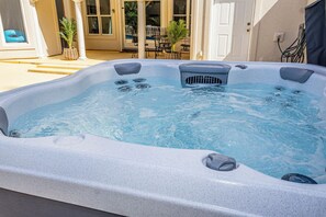 A hot tub with a built-in heater, surrounded by a patio area with outdoor furniture and plants.
