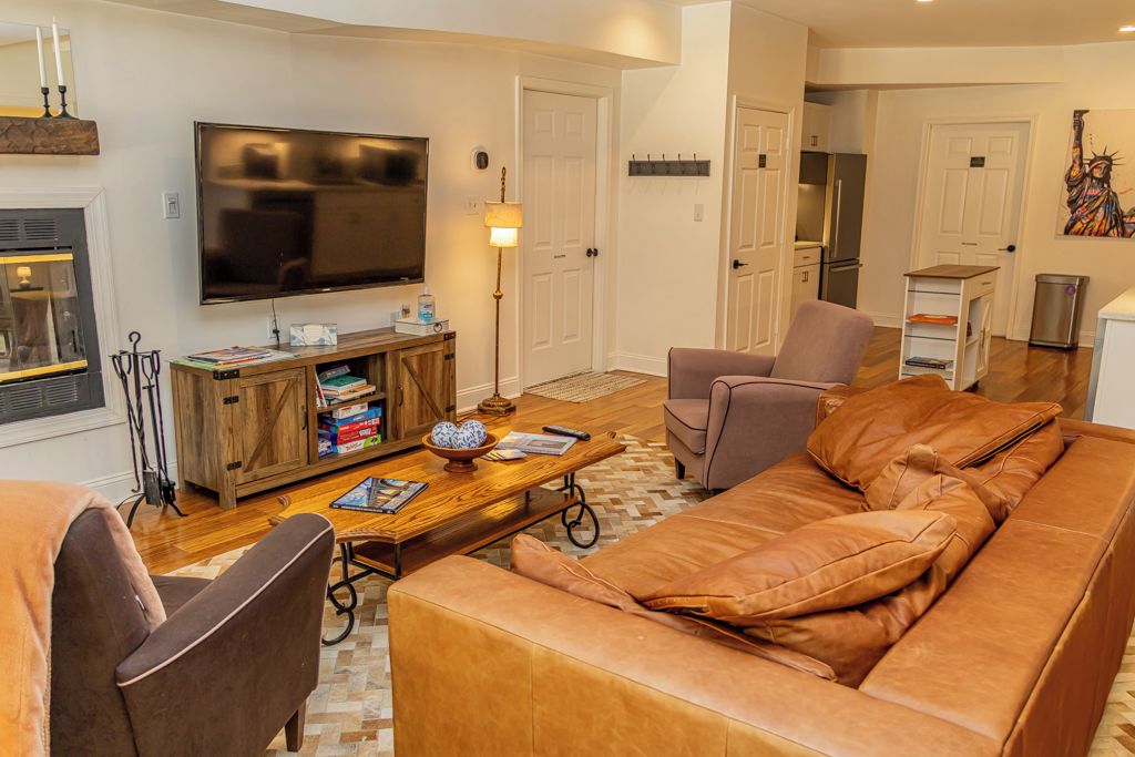 A living room with a leather sofa, a television, a wooden coffee table, and a fireplace.