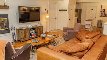 A living room with a leather sofa, a television, a wooden coffee table, and a fireplace.