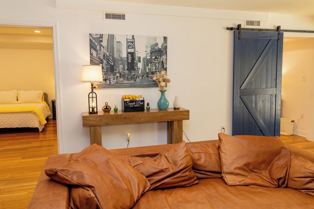 A bedroom with a bed, a nightstand, a lamp, a picture, and a sliding door.