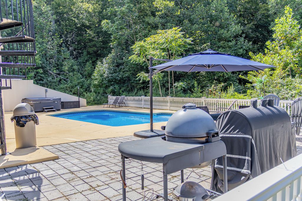 A backyard with a swimming pool, barbecue grill, and outdoor seating.