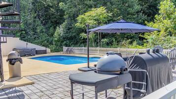 A backyard with a swimming pool, barbecue grill, and outdoor seating.