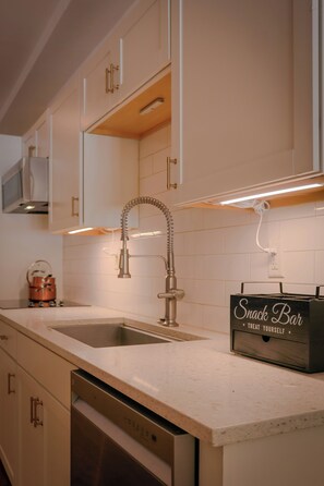 A kitchen with white cabinets, stainless steel appliances, and a 'Snack Bar' sign.