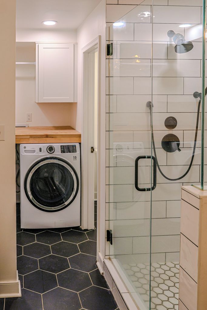 A compact laundry area with a washing machine and a glass-enclosed shower.