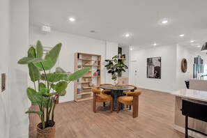 Ein modernes Interieur mit einem runden Tisch, Stühlen, einem Bücherregal und einem Blumentopf.