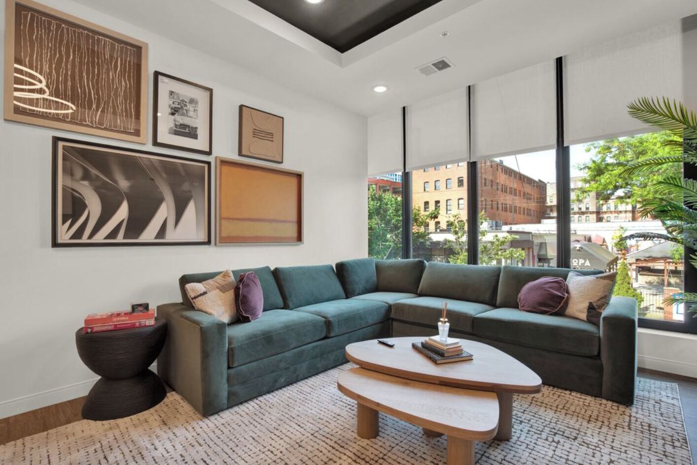 Un salon moderne avec un canapé d’angle, une table basse et des œuvres d’art accrochées aux murs.
