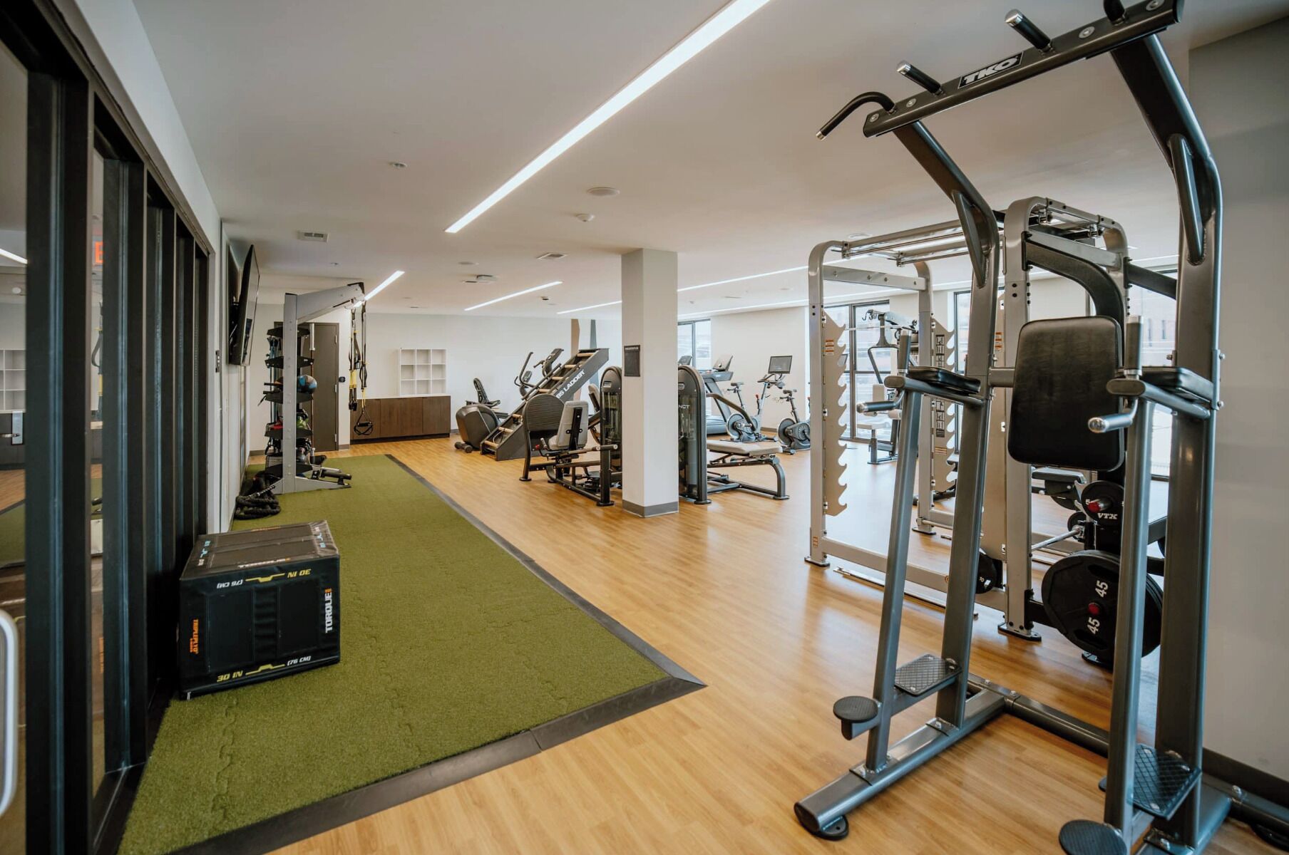 A gym with various exercise equipment, a green mat, and a treadmill.