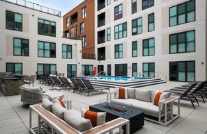 A rooftop pool area with lounge chairs, a barbecue grill, and a fire pit. - Stylish 2BR Suite OTR, Gym, Pool Downtown Access (Cincinnati)