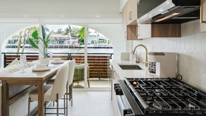 A modern kitchen with a gas stove, white cabinets, and a view of a marina. - The Arches: Waterfront Suite in Boca (Boca Raton)