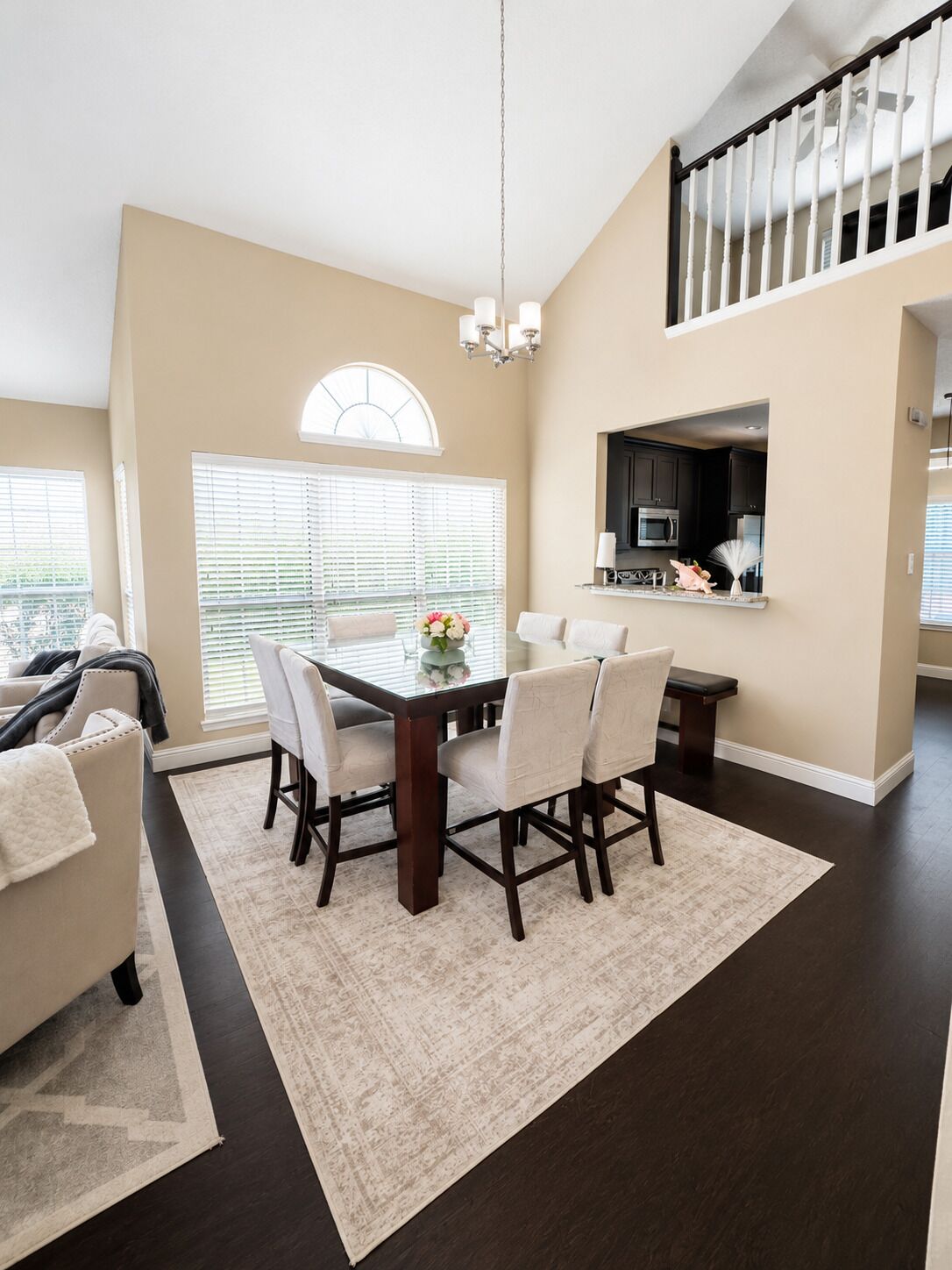 A modern living room with a dining area, a staircase, and a kitchen.
