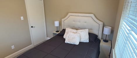 Un dormitorio con cama, ventilador de techo, puerta y ventana con persianas.