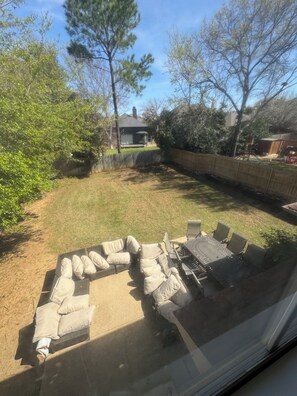 Ein Garten mit Terrasse, Holzfence und einem Haus im Hintergrund.