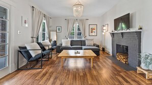A living room with a fireplace, a sofa set, a coffee table, and a chandelier. - 8 Min to Broadway-Hot Tub-Walk to Food &Local Bars (Nashville)