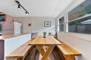Eine Küche mit Holztisch und Bank, weißen Wänden und einem Fenster mit Blick.