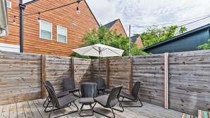 A wooden deck with outdoor furniture, including a table and chairs, and a white umbrella. - 8 Min to Broadway-Hot Tub-Walk to Food &Local Bars (Nashville)