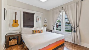 A bedroom with a bed, a guitar, a window with curtains, and a view of the outside. - 8 Min to Broadway-Hot Tub-Walk to Food &Local Bars (Nashville)