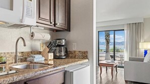 A kitchen with a sink, stove, and refrigerator, and a balcony with a view.