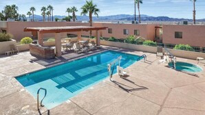 A rooftop pool with lounge chairs, a pergola, and a view of mountains.