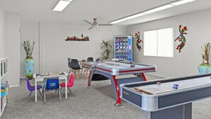 A room with a pool table, chairs, a bookshelf, and a vending machine.