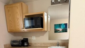 Una cocina compacta equipada con microondas, tostadora, pileta y un refrigerador pequeño.