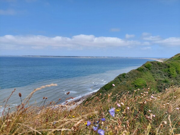 Un paisaje costero con vista al mar y una colina cubierta de hierba.