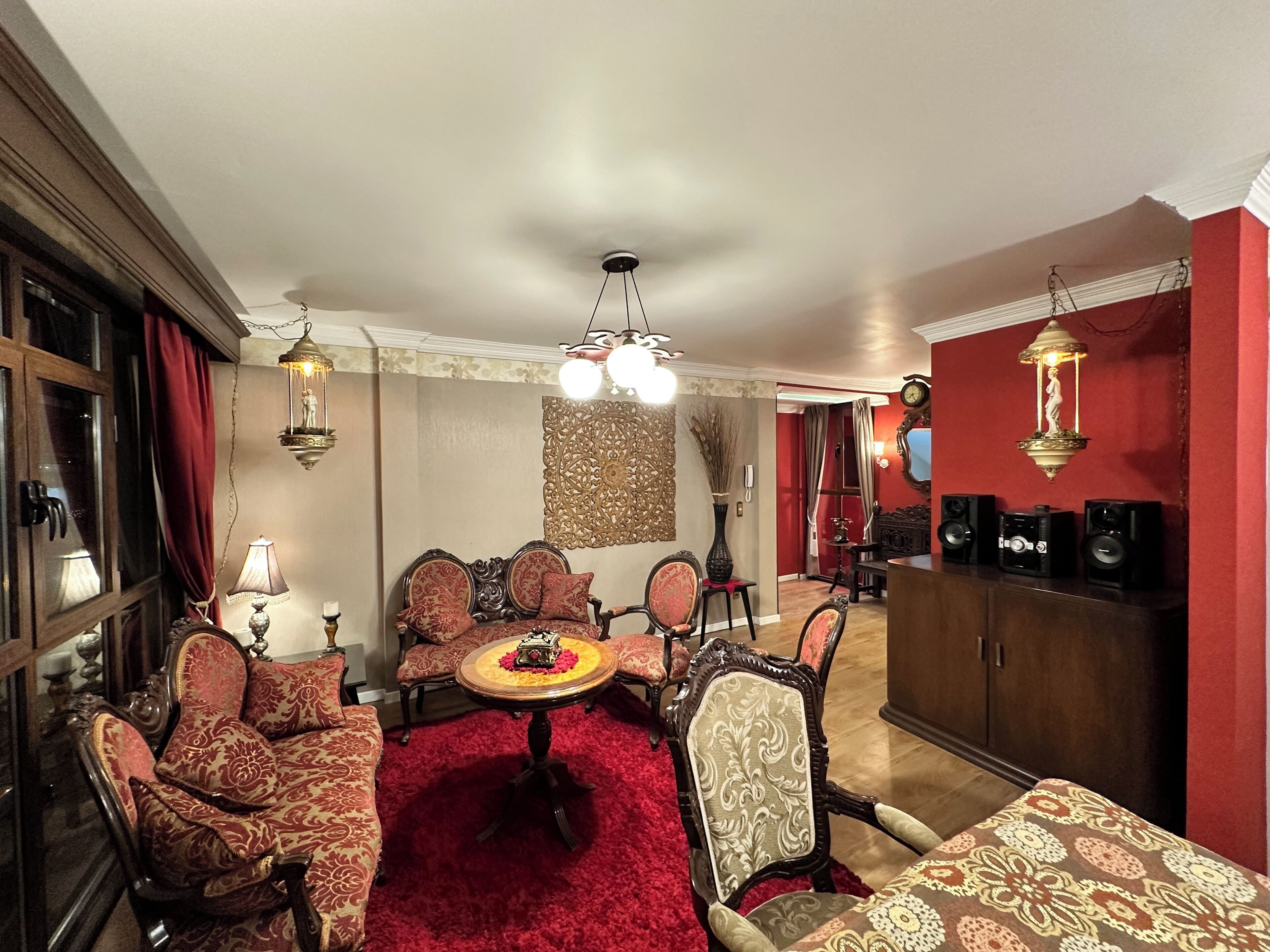 A room with a red carpet, ornate furniture, a chandelier, and a red accent wall.