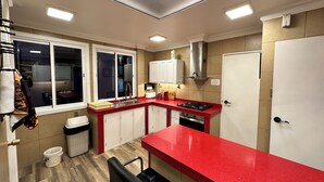 A kitchen with a red countertop, white cabinets, a stainless steel range hood, and a window with a view of the outside. - Vacation Rental (La Paz)
