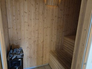 Una sauna de madera con un banco y un pequeño espacio de almacenamiento para piedras.