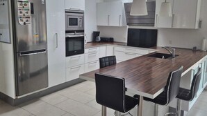 Una cocina moderna con electrodomésticos de acero inoxidable, una isla de madera y taburetes de bar.