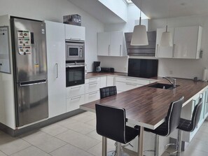 A modern kitchen with stainless steel appliances, a wooden island, and bar stools. - 4 Star Holiday Home in Grenaa (Grenaa)
