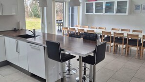 Una cocina moderna con una isla central, taburetes de bar y un comedor con sillas.