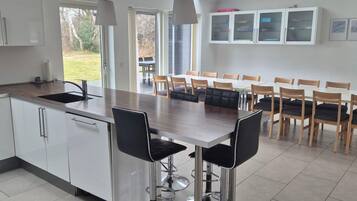 Una cocina moderna con una isla central, taburetes de bar y un comedor con sillas.