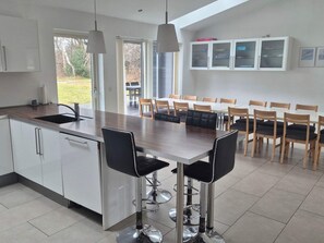 A modern kitchen with a central island, bar stools, and a dining area with chairs. - 4 Star Holiday Home in Grenaa (Grenaa)