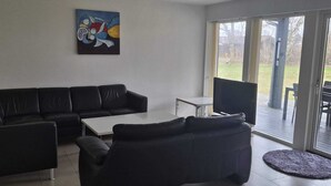 Una sala de estar moderna con un sofá de cuero negro, una mesa de centro blanca y un cuadro en la pared.