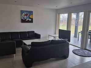 A modern living room with a black leather sofa, a white coffee table, and a painting on the wall. - 4 Star Holiday Home in Grenaa (Grenaa)