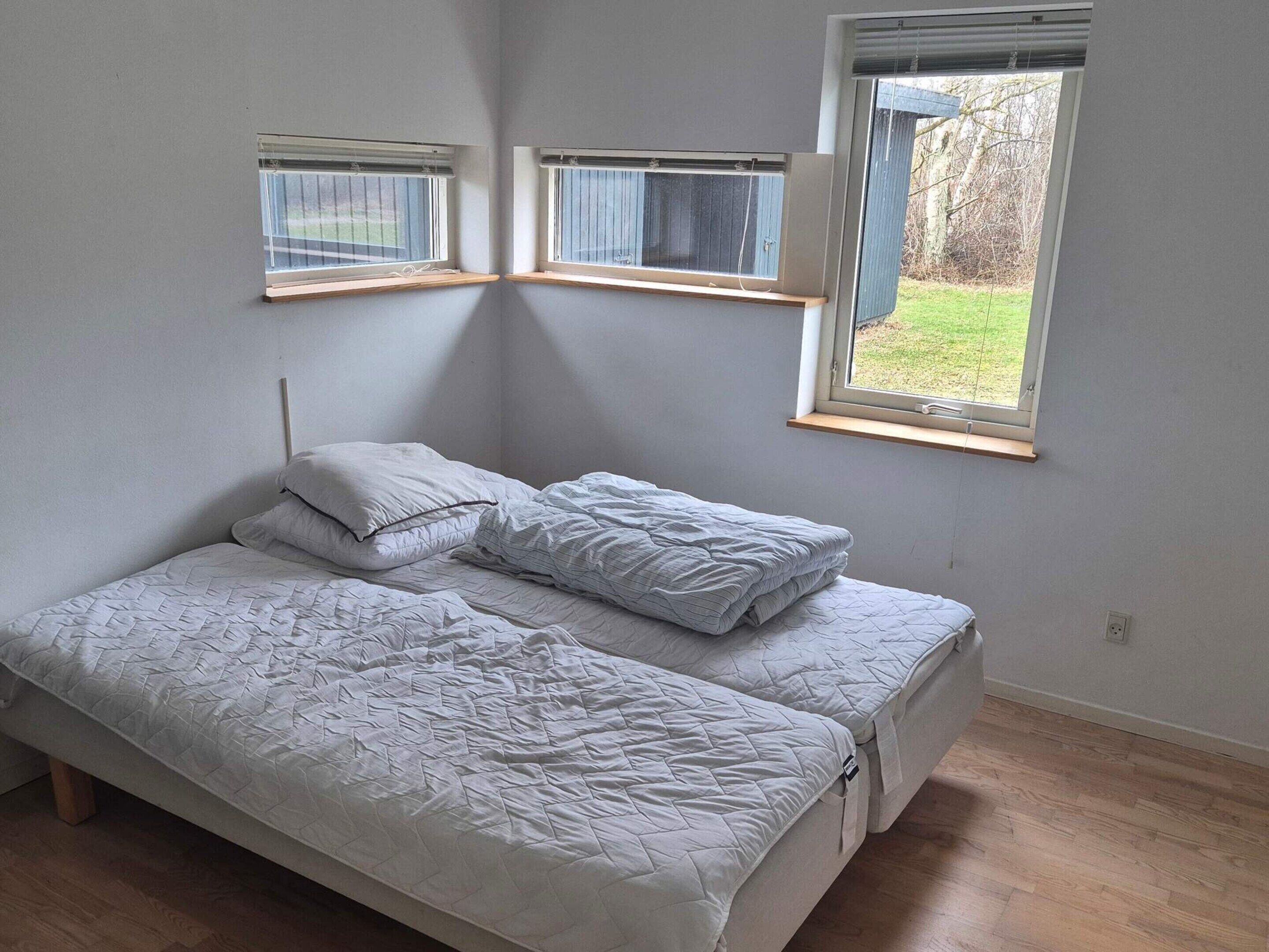 A bedroom with a bed, two windows, and a view of the outdoors.
