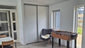 Una habitación con mesa de fútbol, una silla, una mesa y una puerta corredera.