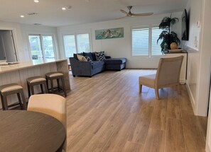 Ein modernes Wohnzimmer mit Sofa, Esstisch und Barbereich.